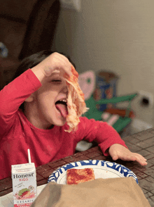 a child eating a slice of pizza next to a carton of honest pizza sauce