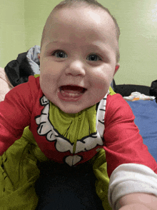 a baby in a grinch costume is smiling