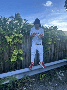 a man wearing a white shirt that says jordan is standing on a railing