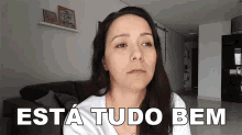 a woman is sitting in a living room with the words " esta tudo bem " on her face