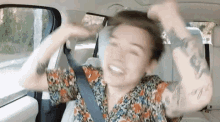 a man is sitting in the back seat of a car with his hands in the air .
