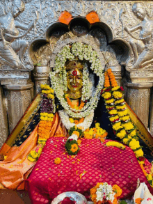 a statue of a deity with flowers around her head