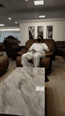 a man wearing a face mask sits in a recliner in a furniture store