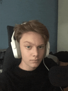 a young man wearing white headphones looks at the camera