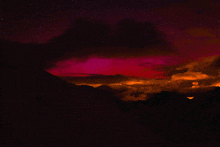 a sunset with mountains in the foreground and a purple sky in the background