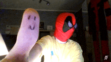 a man wearing a spider man mask holds up a purple object with a face drawn on it