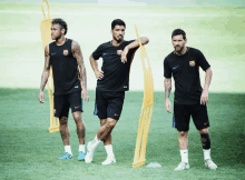 three soccer players are standing on a field with one wearing a shirt that says fc barcelona