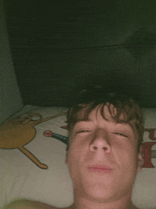 a young man laying on a bed with a cartoon character on the bedspread