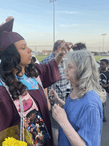 a woman in a graduation cap and gown has a picture of a man on the cape