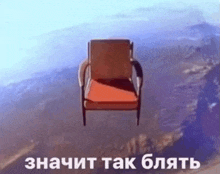 a red chair is flying through the air in front of a mountain .