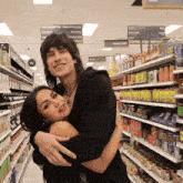 a man is hugging a woman in a grocery store with a sign above them that says ' potatoes '