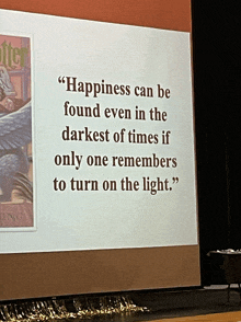 a projector screen displays a quote about happiness