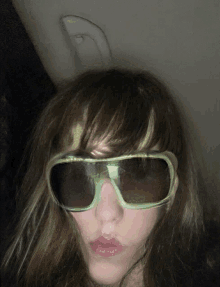 a woman wearing a pair of green sunglasses is making a funny face