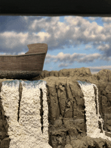 a boat is sitting on top of a rocky cliff near a waterfall