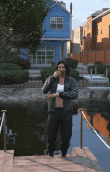 a man standing on a dock smoking a cigarette with a blue house in the background