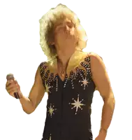 a man singing into a microphone wearing a black top with stars
