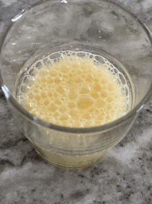 a glass filled with yellow liquid with bubbles in it