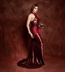 a woman in a red sequined dress holds a glass of wine