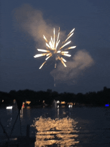 a fireworks display over a lake with boats in the background