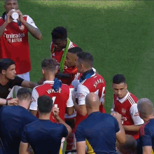 a group of soccer players on a field one of whom is wearing a jersey that says emirates fly better