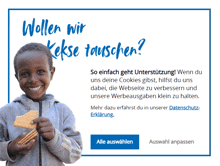 a boy is smiling while holding a cookie in front of a sign that says wollen wir kekse tauschen