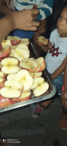 a person holding a tray of sliced apples with a redmi note 8 ai quad camera