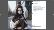 a woman wearing a maroon and white varsity jacket is standing on a sidewalk