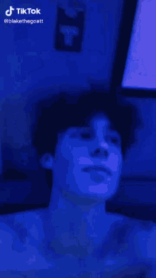 a man 's face is lit up with a blue light and the words tiktok are on the bottom