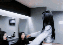 a woman with long black hair stands in front of a mirror