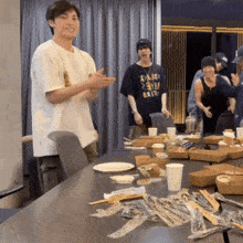 a man wearing a black shirt that says ' a ' on it stands in front of a table full of food