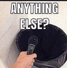 a person holding a microphone in front of a trash can that says " anything else "