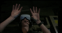 a man wearing a virtual reality headset with his hands up