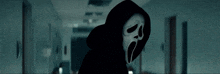 a person with a scream mask on their face is standing in a dark hallway .