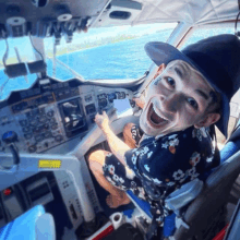 a man in a hat is sitting in the cockpit of an airplane and smiling