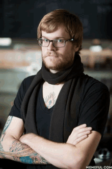 a man with glasses and a scarf around his neck has a tattoo on his arm that says ' loving you '