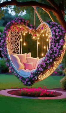 a heart shaped swing is hanging from a tree in a garden decorated with flowers and lights .