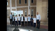 a group of young boys standing in front of a building with a banner that says ' saudi arabia ' on it