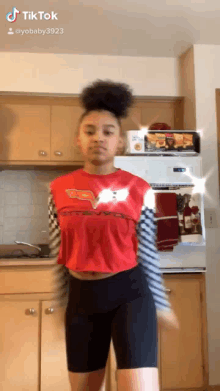 a girl is dancing in a kitchen wearing a red shirt that says cars