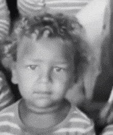 a black and white photo of a little boy with curly hair