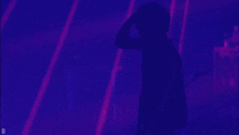 a man stands in front of a purple light with the letter d on the bottom right