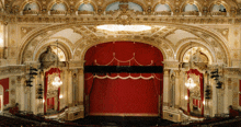 an empty theater with a red curtain and a ceiling