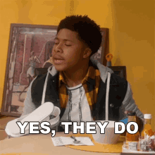 a young man sitting at a table with a bowl of food and the words yes they do above him