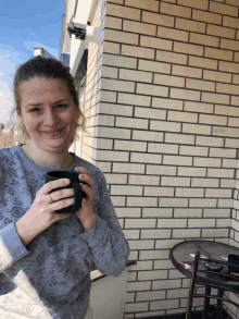 a woman is holding a cup of coffee on a balcony