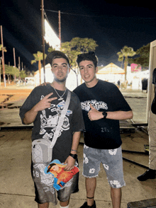 a man wearing a black shirt with the word supreme on it stands next to another man