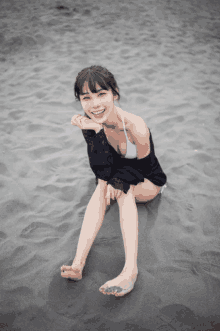 a woman in a bikini is sitting in the sand on the beach