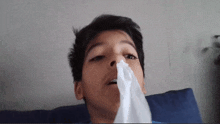 a young boy blows his nose with a napkin