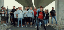 a group of people are standing under a bridge and one of them is wearing a sweatshirt that says ' n '