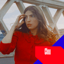 a woman in a red shirt is standing in front of a bridge with the word clou in white