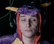 a man is wearing a purple dragon costume with horns and a microphone .