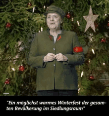 a woman in a green jacket stands in front of a christmas tree with a star on it